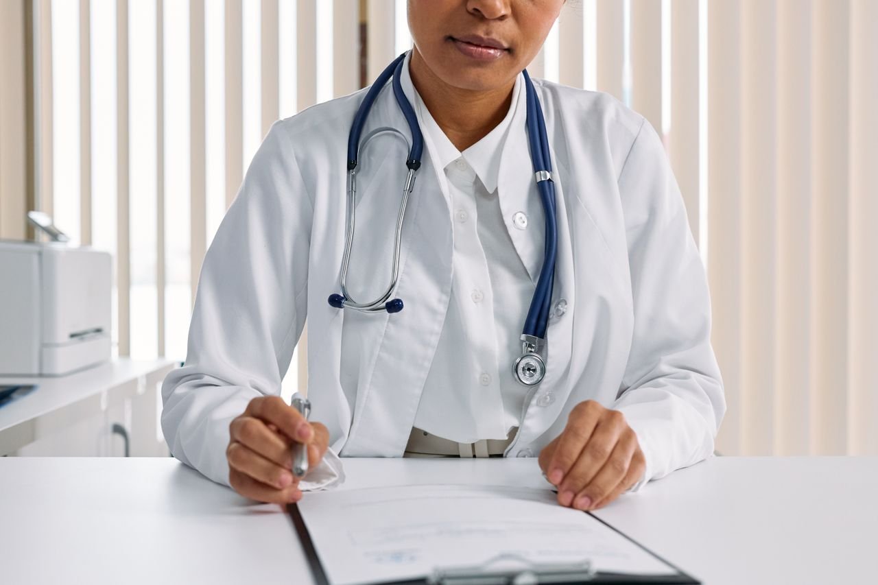 Services-02 A focused doctor with stethoscope recording patient details in an office setting.