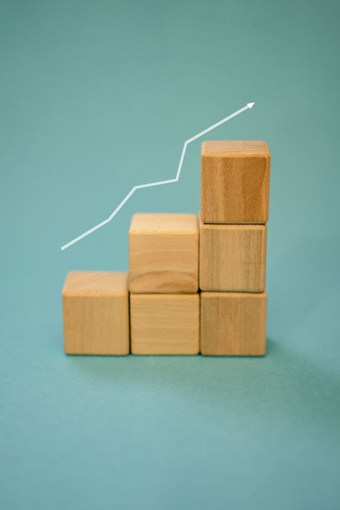 creative-02 Wooden blocks forming a staircase with an upward arrow symbolizing growth and progress.